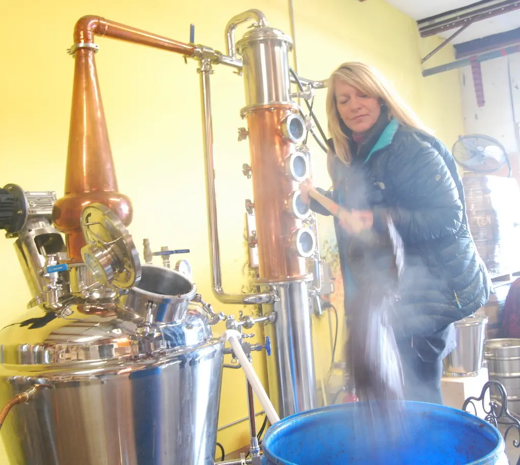 Amy Groth distilling spirits on a copper still